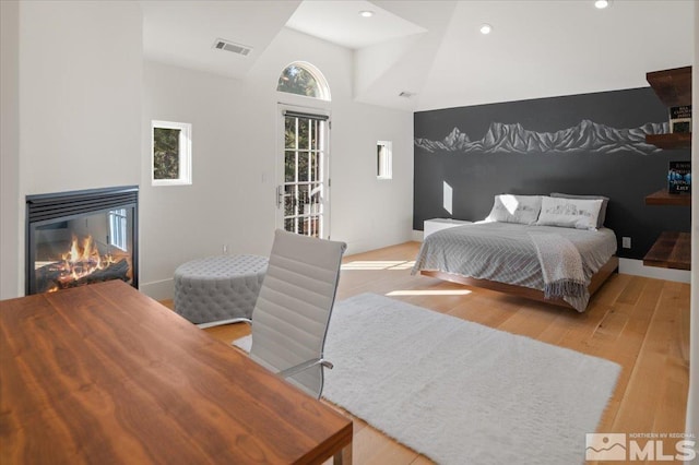 bedroom featuring high vaulted ceiling, light hardwood / wood-style floors, and access to outside