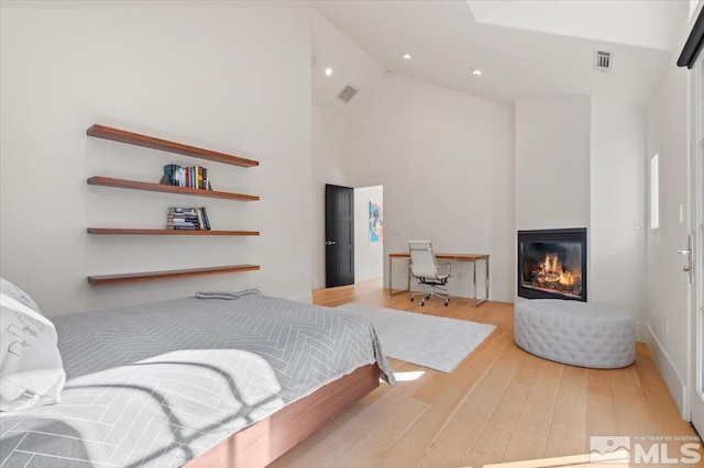 bedroom featuring light wood-type flooring and high vaulted ceiling