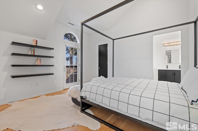 bedroom featuring light hardwood / wood-style floors, connected bathroom, and lofted ceiling