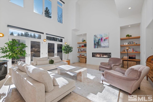 living room with built in shelves, a high ceiling, and french doors