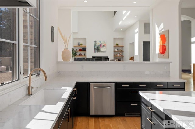 kitchen with light stone counters, sink, stainless steel dishwasher, and light hardwood / wood-style floors