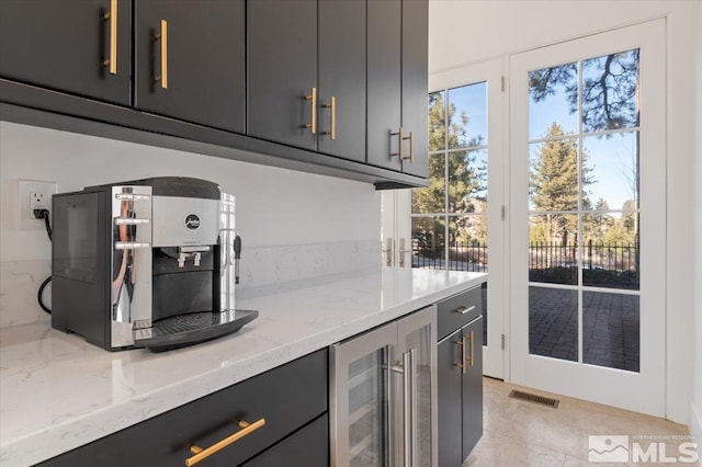 kitchen with gray cabinetry, light tile patterned floors, beverage cooler, and light stone counters