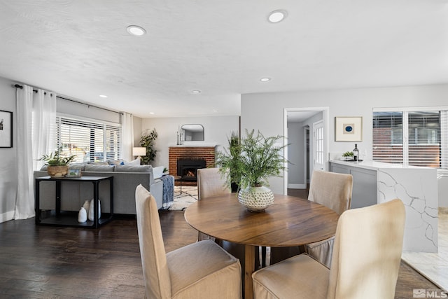 dining space featuring a brick fireplace and dark hardwood / wood-style flooring