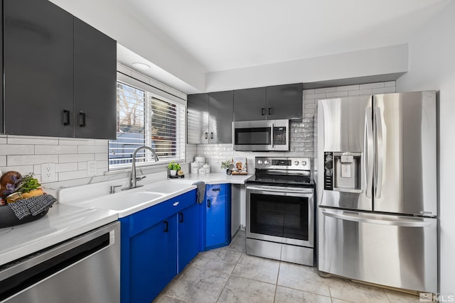 kitchen with appliances with stainless steel finishes, sink, backsplash, light tile patterned floors, and blue cabinets