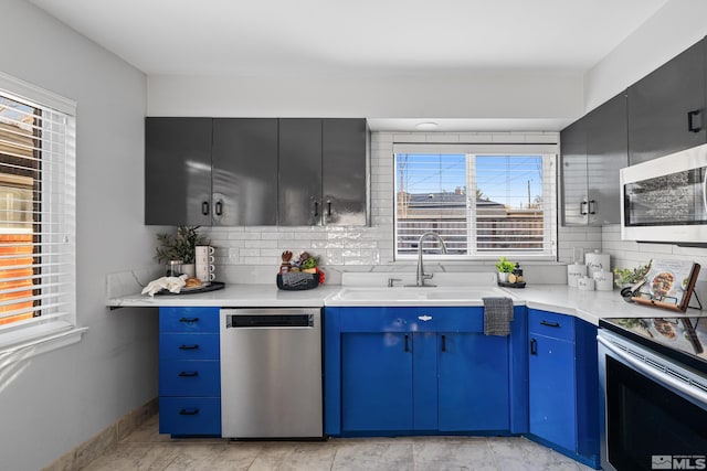 kitchen featuring sink, blue cabinetry, decorative backsplash, and stainless steel appliances