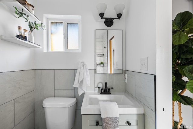 bathroom featuring toilet, tile walls, and vanity