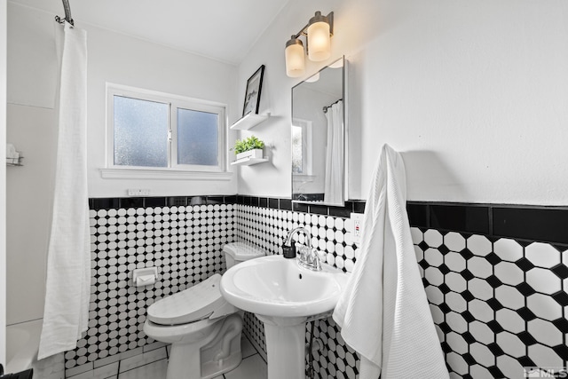 bathroom with tile patterned floors, tile walls, and toilet