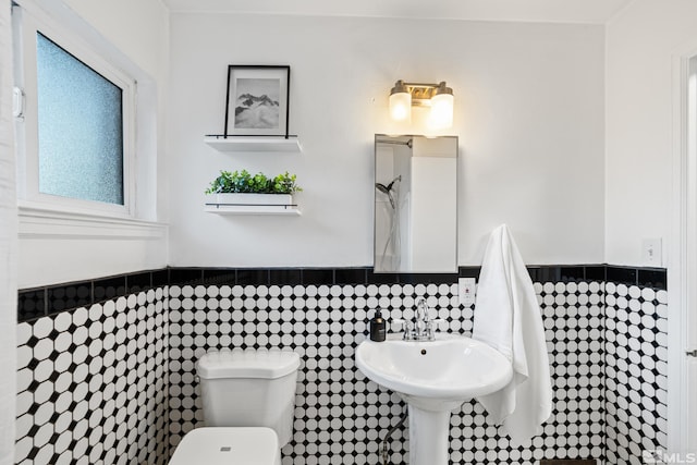 bathroom with sink, toilet, and tile walls