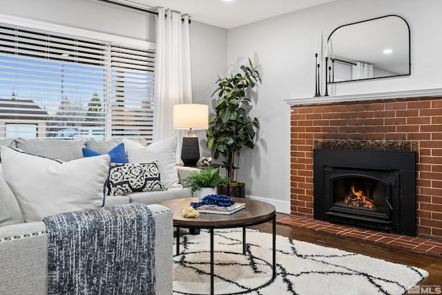 living room featuring a brick fireplace and dark wood-type flooring