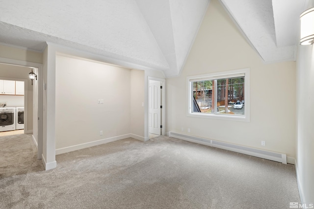 empty room featuring baseboard heating, a textured ceiling, washing machine and dryer, vaulted ceiling, and light colored carpet