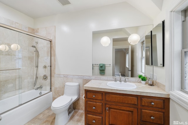 full bathroom with vanity, toilet, bath / shower combo with glass door, and tile walls