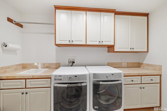 clothes washing area with cabinets, sink, and washing machine and clothes dryer