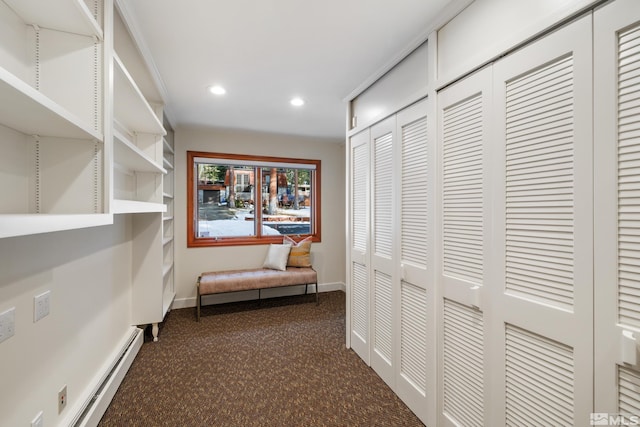 hall with a baseboard heating unit and dark carpet