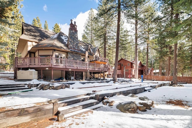 snow covered back of property featuring a wooden deck