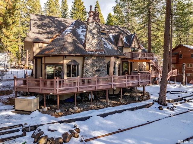 snow covered back of property featuring a wooden deck