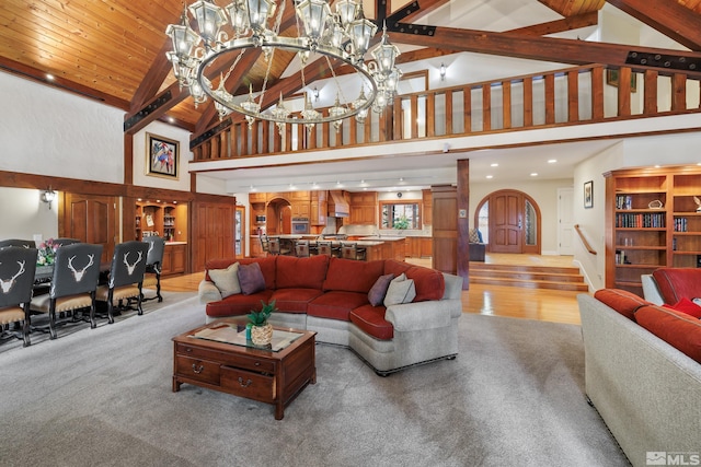 carpeted living room featuring an inviting chandelier, beam ceiling, high vaulted ceiling, and wood ceiling