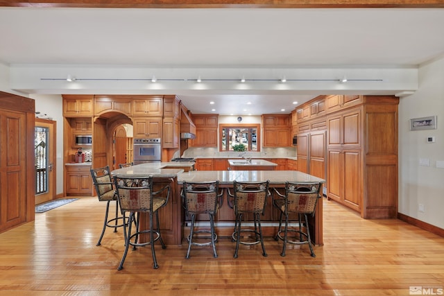 kitchen featuring stainless steel appliances, a kitchen breakfast bar, sink, a large island, and light stone counters