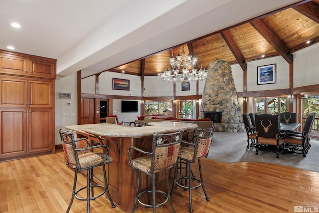 kitchen featuring light wood-type flooring, beam ceiling, wood ceiling, a kitchen bar, and high vaulted ceiling