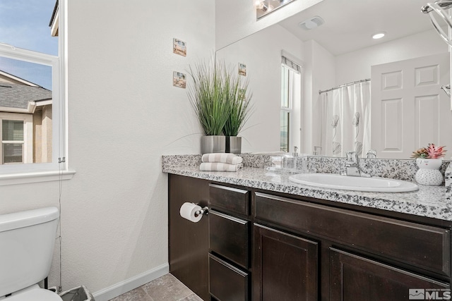 bathroom featuring plenty of natural light, toilet, walk in shower, and vanity