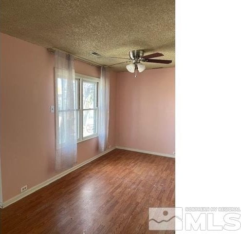 spare room featuring wood-type flooring, a textured ceiling, and ceiling fan