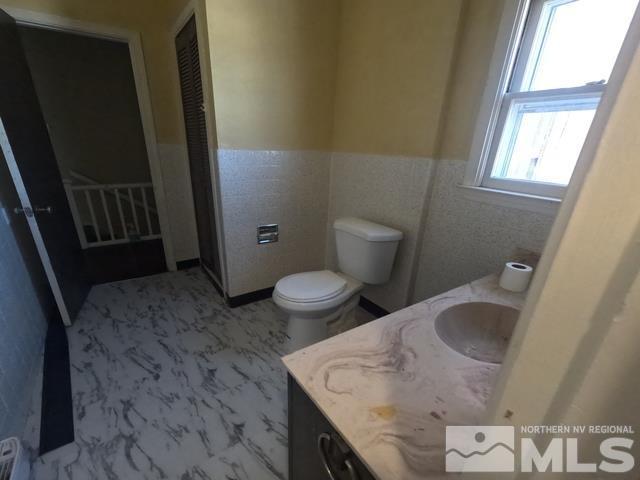 bathroom featuring toilet, tile walls, and vanity