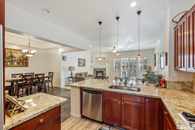 kitchen featuring light stone countertops, sink, pendant lighting, and stainless steel dishwasher