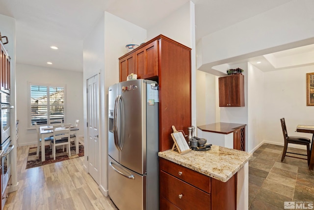 kitchen with light stone counters, appliances with stainless steel finishes, and light hardwood / wood-style flooring