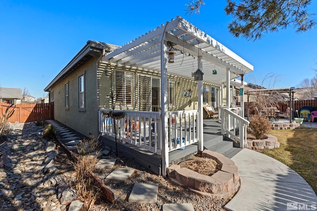 exterior space featuring a deck, a pergola, a patio area, and a fire pit