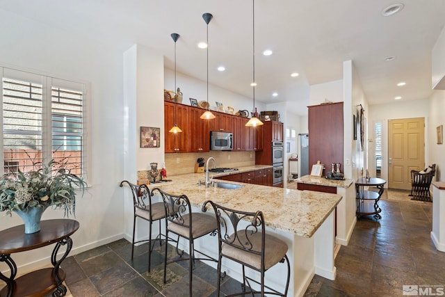 kitchen featuring appliances with stainless steel finishes, decorative backsplash, hanging light fixtures, kitchen peninsula, and light stone counters