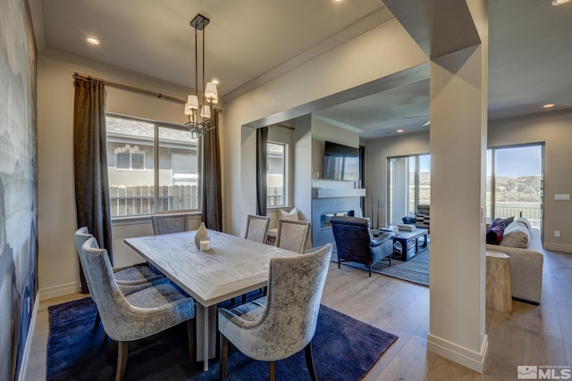 dining room with light hardwood / wood-style floors, a notable chandelier, a wealth of natural light, and ornamental molding