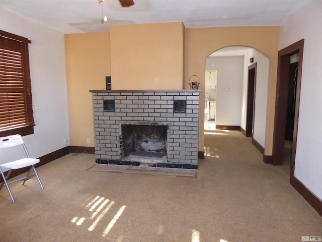 unfurnished living room with a brick fireplace, light carpet, and ceiling fan