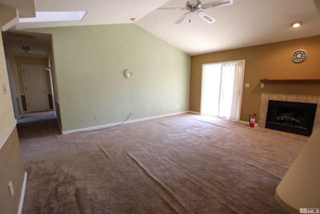 unfurnished living room featuring ceiling fan, vaulted ceiling with skylight, carpet, and a fireplace