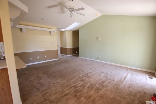 spare room featuring ceiling fan, vaulted ceiling with skylight, and carpet flooring