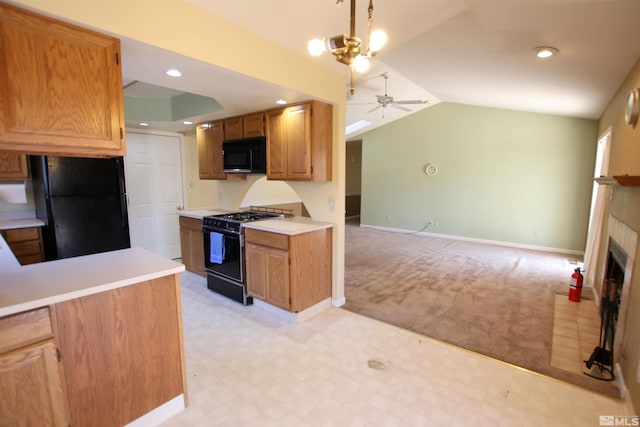 kitchen featuring ceiling fan with notable chandelier, black appliances, lofted ceiling, light carpet, and a tiled fireplace