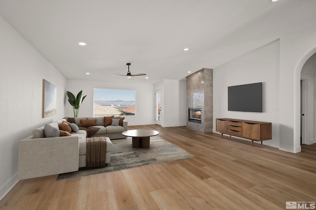 living room with ceiling fan, light hardwood / wood-style floors, and a fireplace