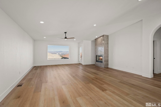 unfurnished living room with ceiling fan, light hardwood / wood-style flooring, and a fireplace