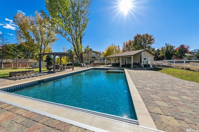 view of swimming pool featuring an outbuilding, a patio, and a pergola