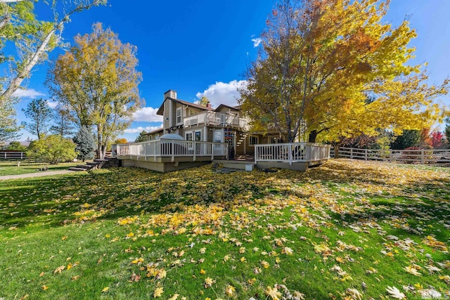 rear view of house featuring a lawn and a wooden deck