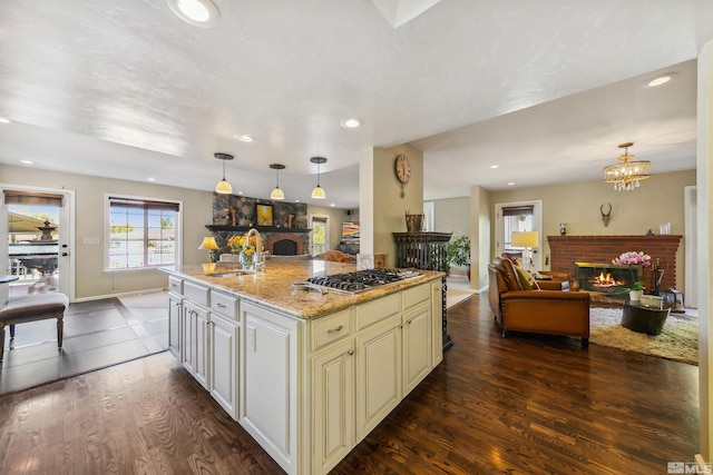 kitchen with sink, pendant lighting, a center island, and a brick fireplace