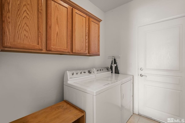 clothes washing area featuring light tile patterned floors, cabinets, and washer and dryer