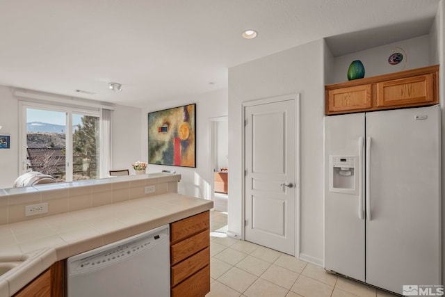 kitchen with white appliances, tile counters, and light tile patterned flooring