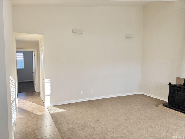 unfurnished living room with light tile patterned floors and a wood stove