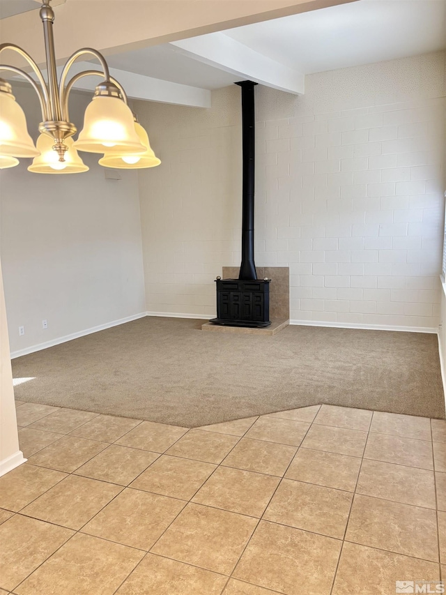 unfurnished living room featuring light carpet, beam ceiling, and a wood stove