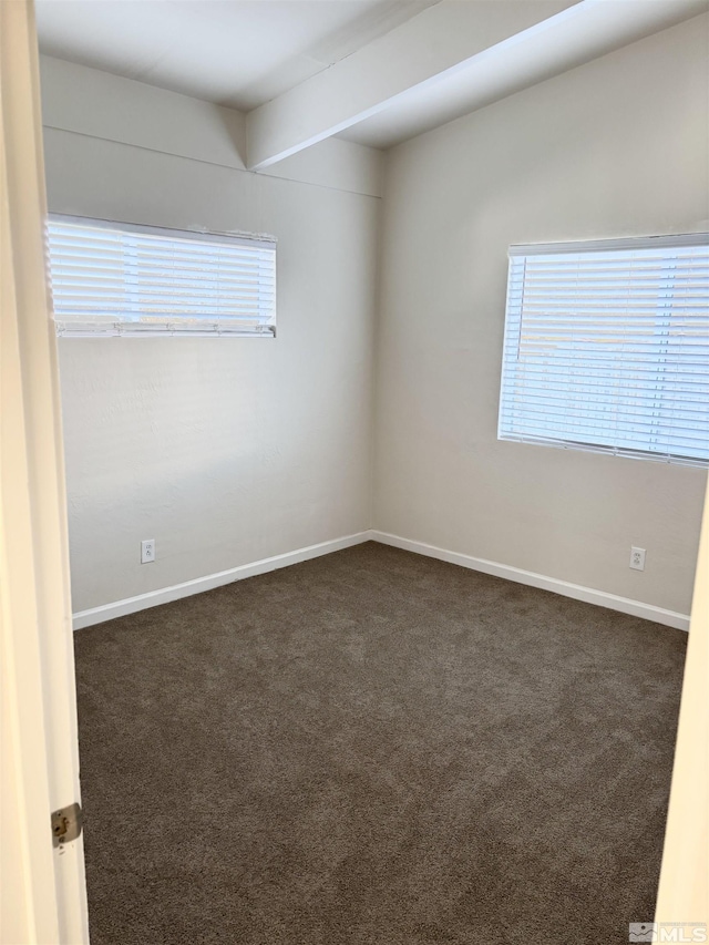 carpeted spare room with a wealth of natural light and beamed ceiling