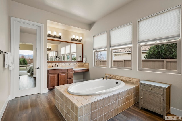 bathroom with vanity, hardwood / wood-style flooring, and a relaxing tiled tub