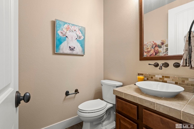 bathroom featuring toilet, tasteful backsplash, and vanity