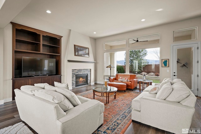 living room featuring a stone fireplace and dark hardwood / wood-style flooring