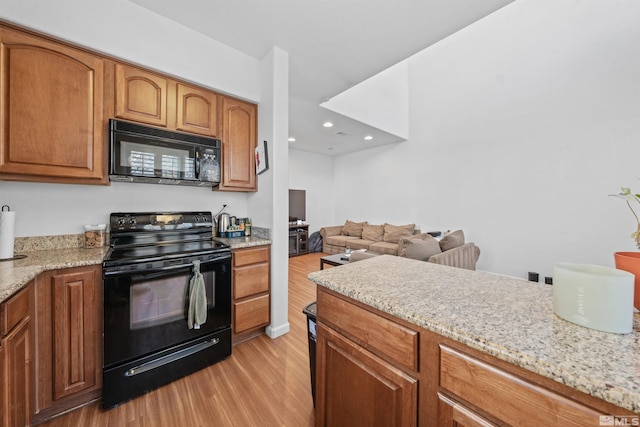 kitchen with black appliances, light hardwood / wood-style flooring, and light stone counters