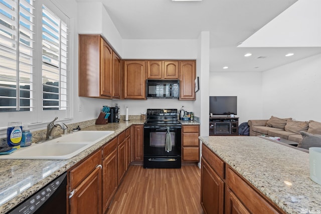 kitchen featuring sink, black appliances, light stone countertops, and light hardwood / wood-style floors