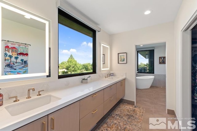 bathroom with tile patterned flooring, vanity, plenty of natural light, and a tub to relax in